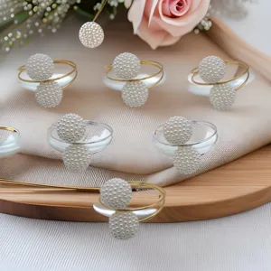 Gold metal napkin rings with white pearl double ball design for elegant hotel and home table decor.