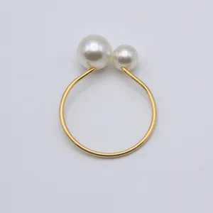 Close-up detail of the gold napkin ring with dual white pearls, elegant table decor style.