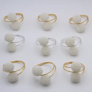 Golden and silver metal napkin rings with double pearl balls for elegant table decor hotel use.