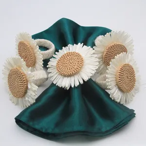 Vista detallada de anillos para servilletas de girasol de paja tejida con servilleta verde.