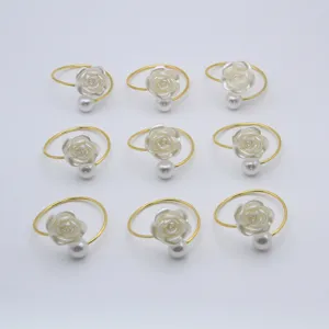 Gold napkin ring with white rose and pearl detail, elegant table decor detail view.