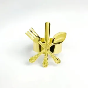 Golden metal napkin ring detail featuring miniature fork knife spoon cutlery decor for elegant tables.