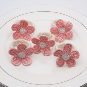 Handmade crochet flower napkin ring detail, soft pink woolen fabric dining table decor set.