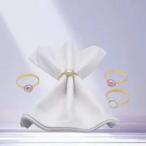 Gold metal napkin rings with iridescent gemstone cabochons for elegant hotel table settings.