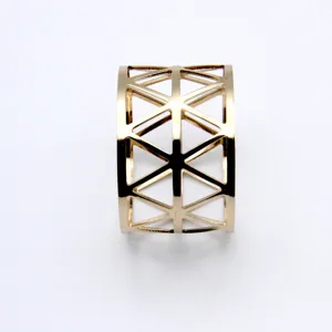 Detail shot of the golden metal napkin ring featuring an intricate geometric hollow design.