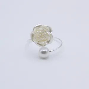 Close-up detail of the elegant silver-tone napkin ring featuring a white rose and pearl charm.