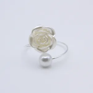 Detailed close-up of a elegant silver tone napkin ring featuring a white rose and a pearl.