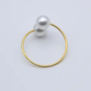 Primer plano del lujoso servilletero de metal dorado con elegantes detalles de perlas dobles.