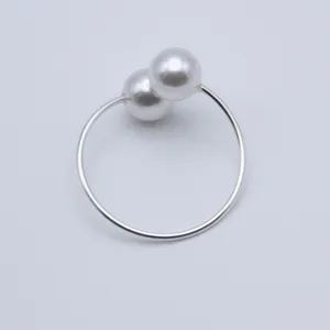 Close-up of elegant silver double pearl napkin ring, minimalist table decor accessory.