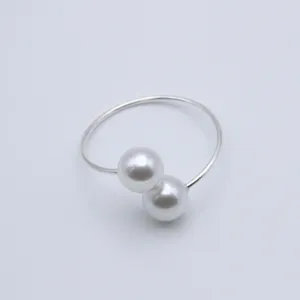 Detail shot of an elegant double pearl napkin ring, minimalist silver metal holder for table decor.