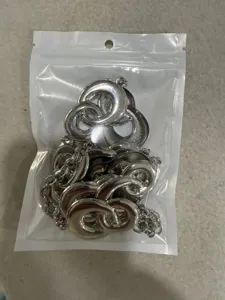 Dettaglio catena da cintura geometrica argentata a forma di 8, accessorio di moda in metallo lucido.