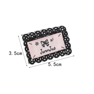 Detailaufnahme des schwarzen Spitzenbroschen-Patches mit rosafarbenem Schleifen-Design.
