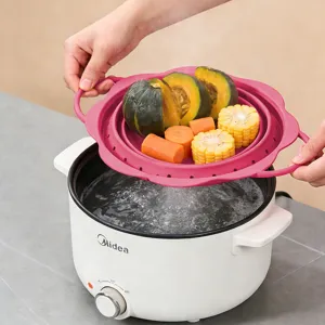 Detail view of a pink foldable silicone colander basket shown steaming food over a pot.