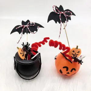 Detailed view of Halloween pumpkin bucket and black cauldron with cute bat toppers and festive decor.