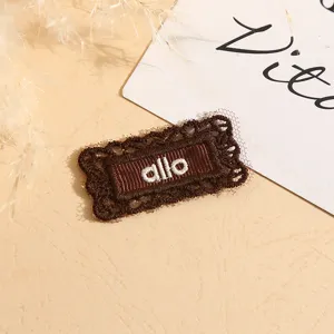 Brown lace embroidered clothing tag detail shot showcasing delicate texture and neat stitching.