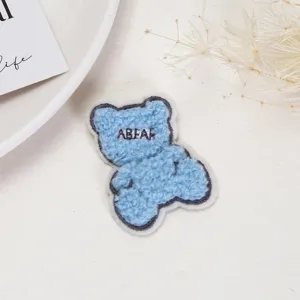Detailed view of a cute blue plush bear embroidery patch, perfect for clothing DIY.