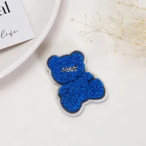 Blue plush bear patch detail, embroidered design for clothing decoration and DIY crafts.