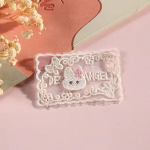 Detailed close-up of cute white lace embroidered patch with bunny motif and English letters.