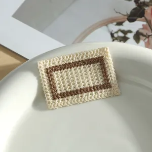 Close-up detail of the cream and brown geometric embroidered patch, showing fine woven texture.