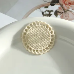 Close-up of beige round embroidered lace patch, delicate hollow-out edge, handmade DIY decor.