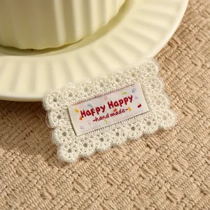 Detailed view of lace embroidered fabric patch with handmade label, perfect for DIY garment decor.