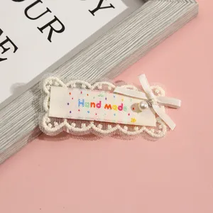 Detailed view of cute handmade lace hair clip with pearl bow and colorful embroidery.
