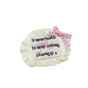 White lace fabric patch with embroidered label and cute pink bow for DIY crafts and decor.