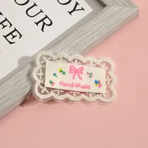 Detailed shot of cute white lace fabric patch with embroidered pink bow and handmade text.