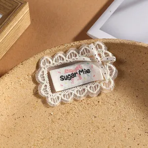 Cute lace hair clip detail shot, decorative bow and embroidered label for stylish daily wear.