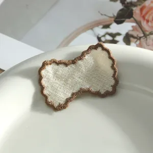 Close-up of a white embroidered DIY patch with brown edge, perfect for clothing and journal decor.