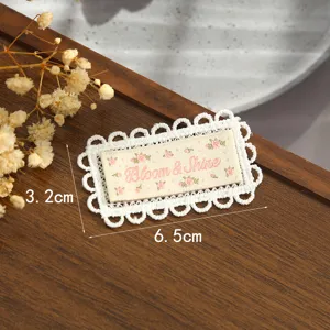 Vue détaillée du patch brodé en dentelle avec des motifs floraux et un texte charmant.
