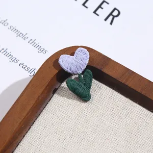 Close-up detail of cute purple heart flower embroidery patch for DIY clothing decor.
