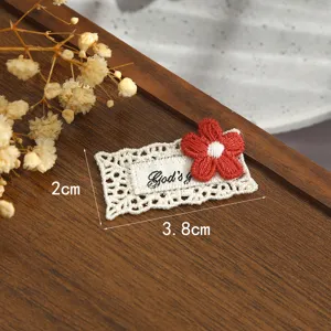 Gros plan d'un patch en dentelle brodé de fleurs rouges avec bordure blanche, motif de tissu détaillé.