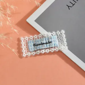 Handmade lace patch fabric applique with blue plaid label for DIY clothing decoration.