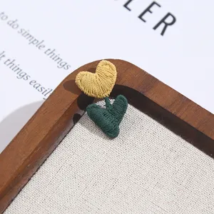 Close-up detail of cute yellow flower embroidery patch with green leaves on fabric board.