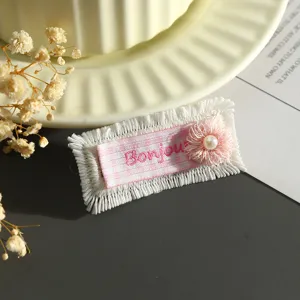 Primo piano dettagliato della toppa in tessuto a quadri rosa con pizzo e ricamo di perle.