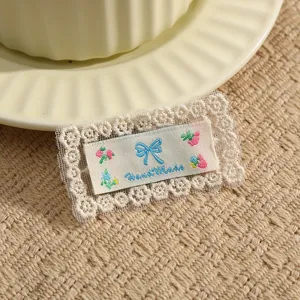 Detail shot of handmade embroidered lace fabric patch featuring cute bow and floral design.