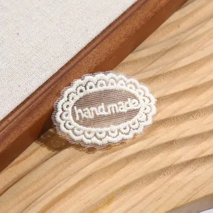 Gros plan détaillé d'un patch de broderie en dentelle ovale blanche avec du texte handmade.