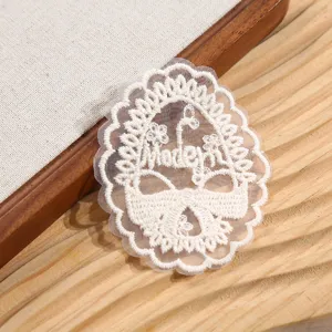 Gros plan d'un patch de broderie en dentelle beige élégant avec un motif floral délicat.