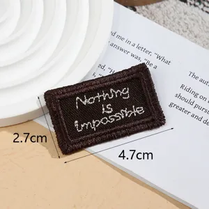 Dark brown embroidered woven fabric patch label with motivational text for diy clothing items.