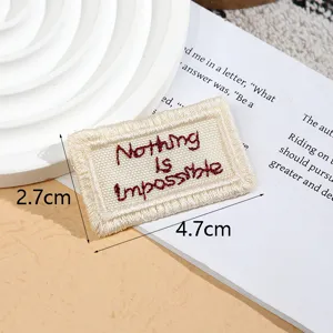 Detailed shot of beige embroidered patch tag with red text for DIY garment accessories.