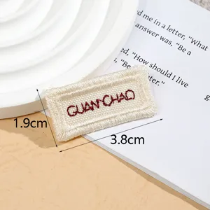 Beige woven fabric clothing label patch, embroidered DIY accessory, 3.8x1.9cm size detail shot.