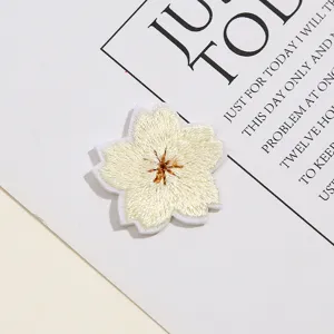 Gedetailleerde close-up van de delicate geborduurde kersenbloesem patch voor handwerk DIY.