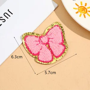 Detailed close-up of the pink bow towel embroidery patch with sparkling gold glitter border.