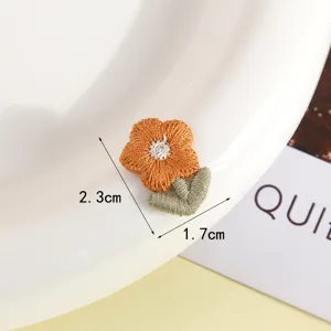 Close up detail of the cute orange flower embroidered cloth patch showing delicate texture.