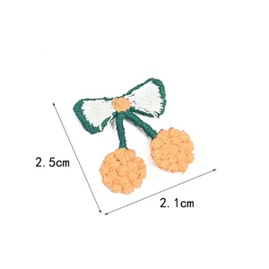 Handcrafted knitted cherry patch with bow, cute DIY clothing accessory and hair clip decor.
