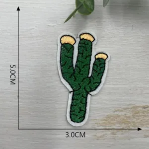 Detailed view of a green cactus embroidered clothing patch with white border and gold top.