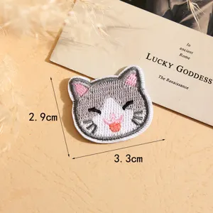 Detailed shot of a cute cartoon cat embroidered patch, grey fabric kitty DIY accessory.