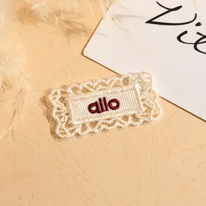 Close-up detail of white lace embroidered clothing patch with allo text design apparel accessory