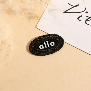 Black oval lace embroidered patch clothing accessory with hollow design and letter print.